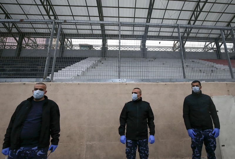 Members of the Palestinian security forces wearing protective masks stand guard during a football match without fans, amid fears of the spread of the novel coronavirus, in the West Bank city of Hebron. AFP