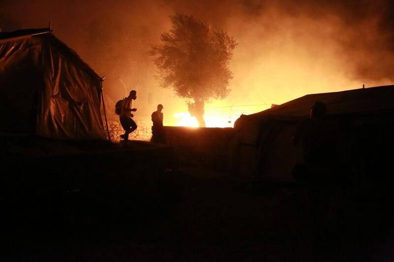 Migrants walk inside the Moria camp on the island of Lesbos during a major fire. AFP