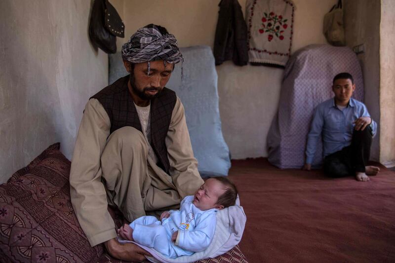 Ahmed Reza, 34, holds his son Abbas at his home in the western outskirts of Kabul, a place of relative calm and safety. His wife Rokaia has been brutally killed in the attack on the maternity ward in Dasht-e-Barchi. 