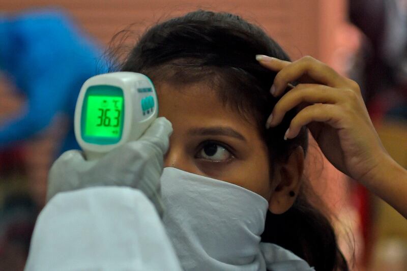 A medical volunteer takes temperature reading of a woman at a coronavirus testing centre in Mumbai on July 17, 2020. AFP