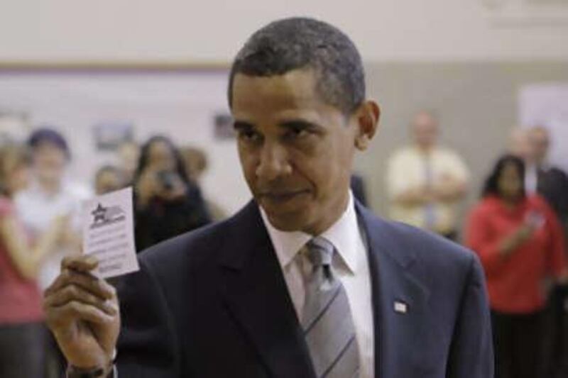 Barack Obama holds up his ballot receipt after voting at a polling station in Chicago.