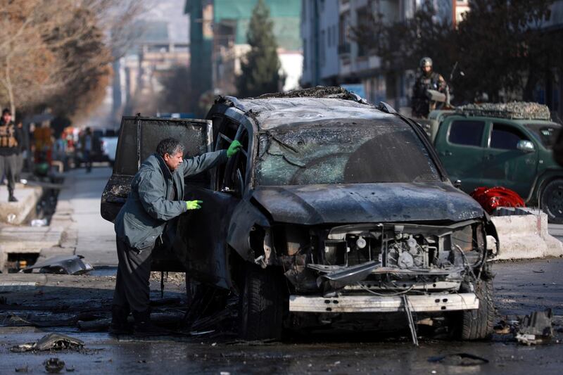 An Afghan security member inspects a damaged vehicle after a bomb blast in Kabul, Afghanistan, Sunday, December 13, 2020. AP
