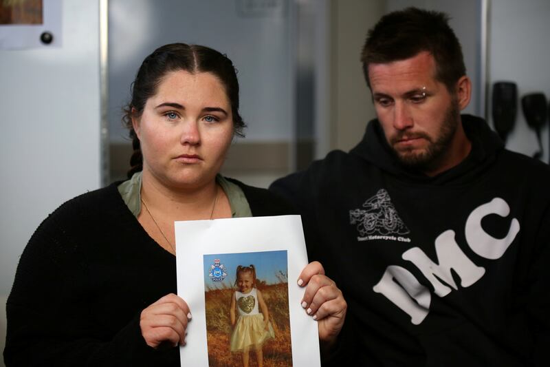 Cleo’s mother Ellie Smith, standing with her partner Jake Gliddon, holds up a photo of her missing daughter. Reuters