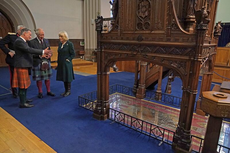 King Charles and Camilla are shown the gravestone of Robert the Bruce during a visit to Dunfermline Abbey. AFP