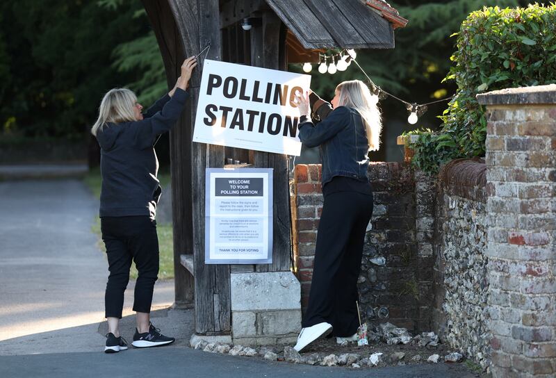 Polling clerks hang a polling station sign outside the entrance archway to Christ Church in Chorleywood. Reuters