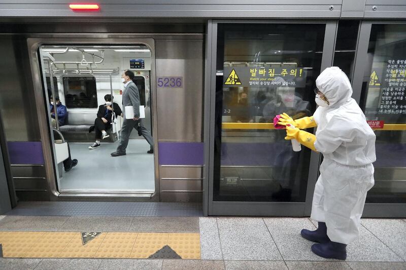 A worker wearing protective gears disinfects a door as a precaution against the new coronavirus at a subway station in Seoul, South Korea, Friday, Feb. 28, 2020. Japan's schools prepared to close for almost a month and entertainers, topped by K-pop superstars BTS, canceled events as a virus epidemic extended its spread through Asia into Europe and on Friday, into sub-Saharan Africa. (AP Photo/Ahn Young-joon)