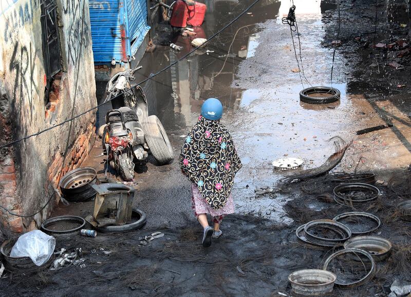 A woman with a helmet walks among debris at a burnt tyre market after clashes in New Delhi, India.  EPA