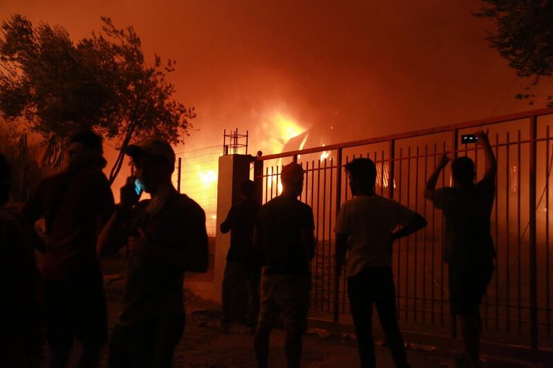 Refuees stand outside the Moria camp on the island of Lesbos during a major fire there.  AFP