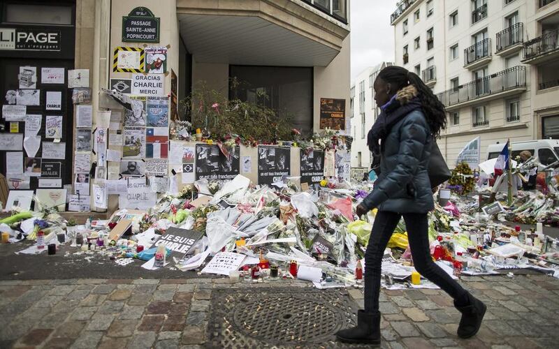 A girl walks past the hundreds of flowers near the Charlie Hebdo offices in Paris. Photo: Ian Langsdon / EPA