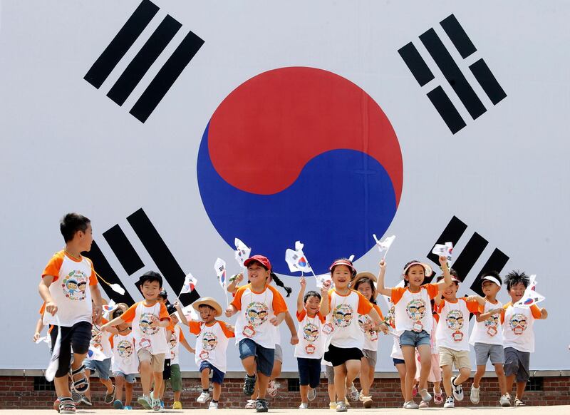 Children run in front of the South Korean national flag in Seoul. Kim Chul-Soo/EPA