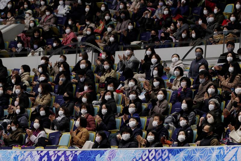 Spectators wearing face masks looks towards an electric board for performance results during a free skating of an ISU Grand Prix of Figure Skating competition in Kadoma near Osaka, Japan. AP Photo