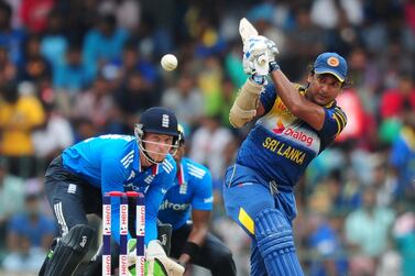 Sri Lankan cricketer Kumar Sangakkara (R) is watched by England wicketkeeper Jos Buttler as he plays a shot during the seventh and final One Day International (ODI) match between Sri Lanka and England at the R. Premadasa Cricket Stadium in Colombo on December 16, 2014. AFP PHOTO / LAKRUWAN WANNIARACHCHI (Photo by LAKRUWAN WANNIARACHCHI / AFP)