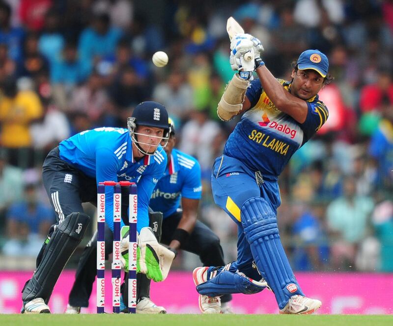 Sri Lankan cricketer Kumar Sangakkara (R) is watched by England wicketkeeper Jos Buttler as he plays a shot during the seventh and final One Day International (ODI) match between Sri Lanka and England at the R. Premadasa Cricket Stadium in Colombo on December 16, 2014. AFP PHOTO / LAKRUWAN WANNIARACHCHI (Photo by LAKRUWAN WANNIARACHCHI / AFP)