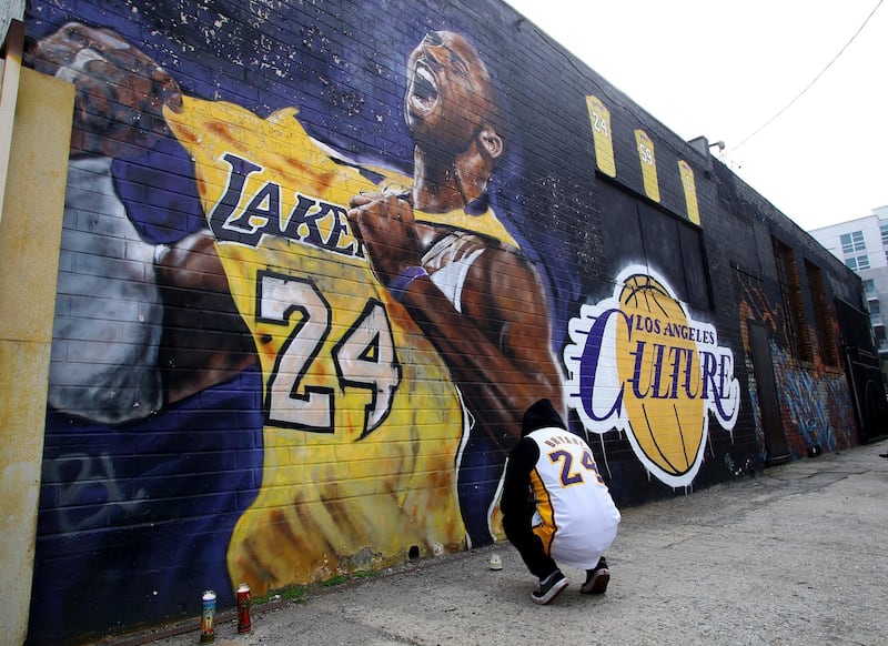 A fan pays respects at a mural depicting Kobe Bryant in a downtown Los Angeles alley after word of the Lakers star's death in a helicopter crash, in downtown Los Angeles Sunday, January 26, 2020. AP Photo/Matt Hartman