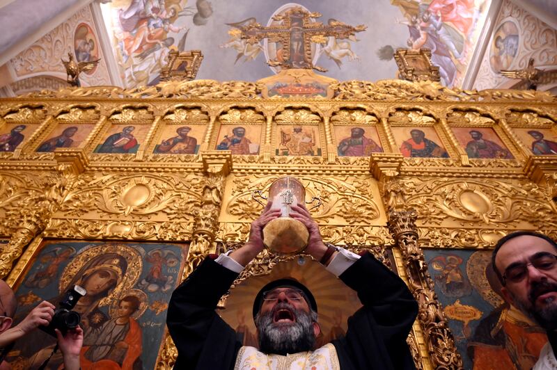 A Greek Orthodox Christian priest holds up the Holy Fire as he arrives at St. George Greek Orthodox Cathedral from Jerusalem through Amman, in Beirut. EPA