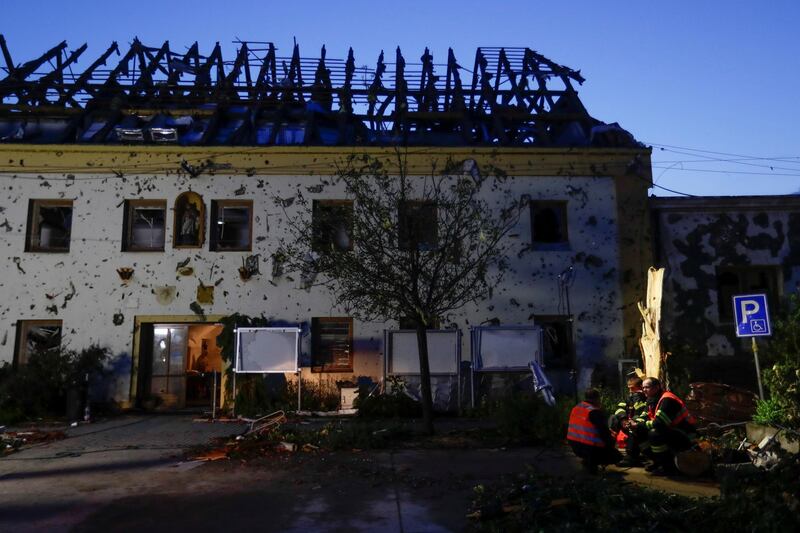 Emergency services personnel sit in front of a building damaged by a rare tornado that struck Moravska Nova Ves, and other villages and towns in the Czech Republic on June 24, 2021. Reuters
