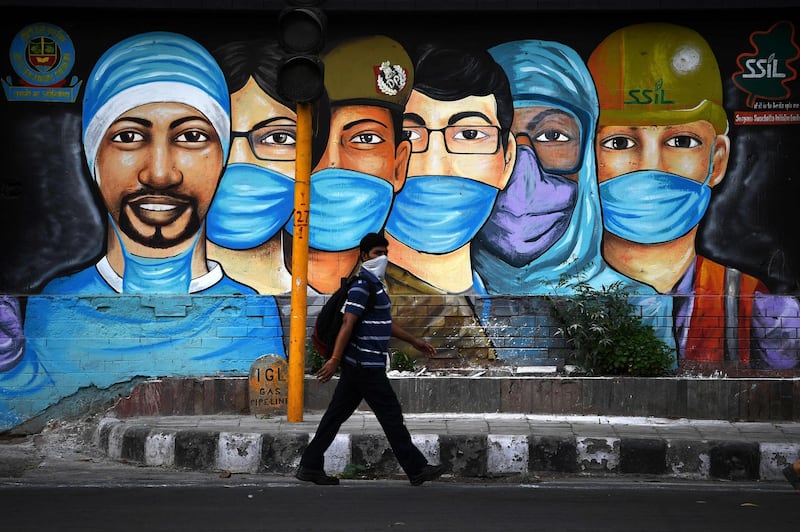 A man walks past a mural of frontline workers after the government eased a nationwide lockdown imposed as a preventive measure against the coronavirus in New Delhi.  AFP