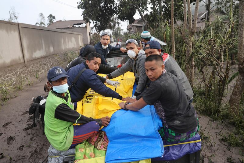 Volunteers and emergency workers carry a victim away from an area affected by the eruption of Mount Semeru. AP