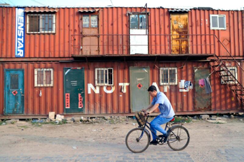 A cyclist passes container shelters in the urban-rural integration area of Qingdao. Wu Hong / EPA