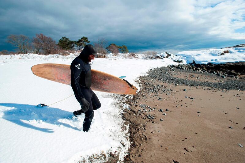 Surfer Jonathan Bee carries his board through the snow to the water at Devereux beach after a snowstorm dumped around 15 inches of snow in Marblehead, Massachusets. AFP