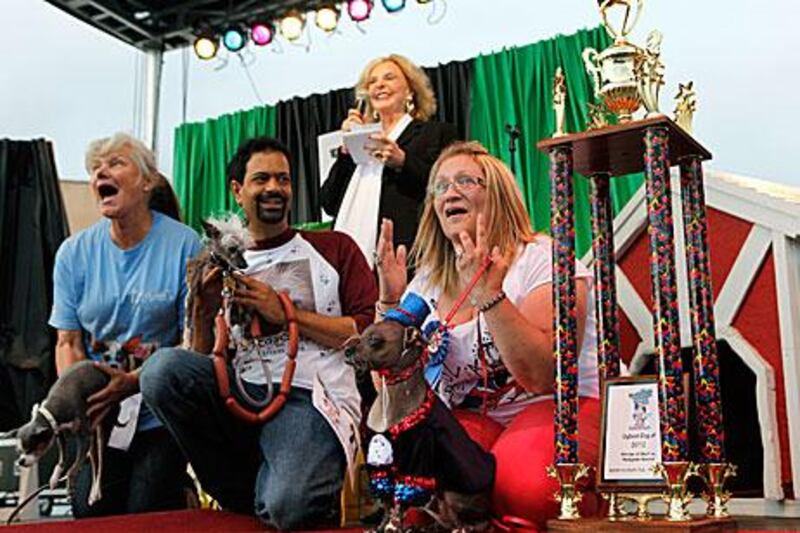 Bev Nicholson, of the UK, hears the announcement of Mugly's victory alongside Dane Andrew and dog Rascal, middle, and Kathleen Francis with Princess Abby. Beth Schlanker / AP Photo/ The Press Democrat