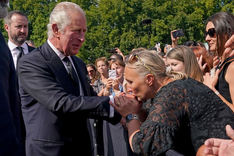 A well-wisher kisses the hand of King Charles III outside  Buckingham Palace after the death on Thursday of Queen Elizabeth II. King Charles, who spent much of his 73 years preparing for the role, on Friday planned to meet the prime minister and address a nation grieving the only British monarch most of the world had known.  He takes the throne in an era of uncertainty for his country and the monarchy itself.  AP
