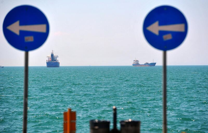 Cargo ships sail on the Mediterranean Sea seen beyond road traffic signs in Thessaloniki, Greece, on Saturday, July 27, 2013. As unemployment hits a record, the Greek parliament adopted last week the final piece of a plan to put 4,200 state employees on notice for dismissal before euro partners signed off on this month's 2.5 billion-euro payment. Photographer: Oliver Bunic/Bloomberg