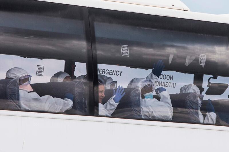 Staff members accompanying South African citizens who have been repatriated from Wuhan, China, where they were working when the COVID-19 novel coronavirus erupted, wave to bystanders as they drive in a police escorted convoy on a bus en route to The Protea Hotel Ranch Resort in Polokwane, where they will be quarantined.   AFP