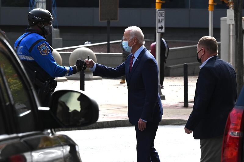 Democratic presidential candidate Joe Biden fists bumps a police officer as he departs The Queen after taping an interview with CBS’ 60 Minutes, in Wilmington, Delaware. AFP