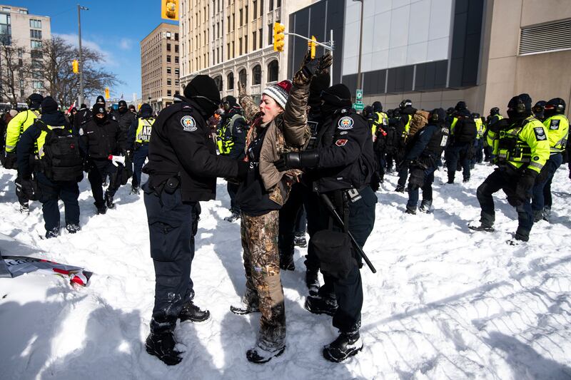 A protester sings 'O Canada' as she is arrested after trying to push through a line of police officers. AP