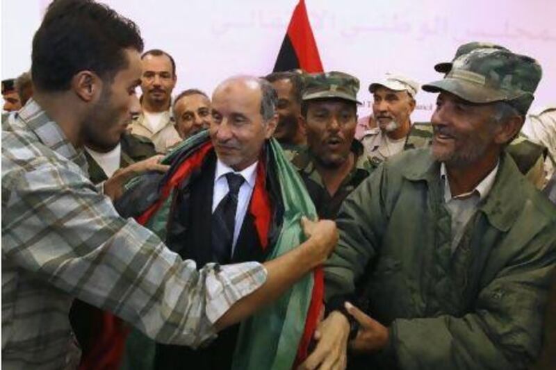 Libyan Transitional National Council chairman Mustafa Abdul Jalil, center, receives a Libyan flag amid Libyan veterans after a press conference in Benghazi Monday. Libya's transitional leader has ordered an investigation into the death of Muammar Qaddafii after the US and other international powers pressed for the probe.