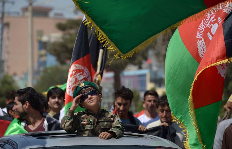 An Afghan boy salutes while dressed in military gear during celebrations to mark the country's Independence Day in Mazar-i-Sharif. Farshad Usyan / AFP.