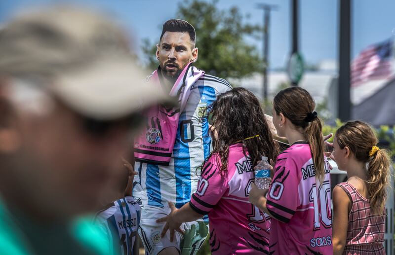 Fans with a cardboard cutout figure of Lionel Messi wait for his arrival to the DRV PNK Stadium. EPA