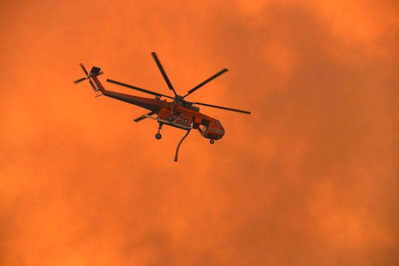 A helicopter prepares to dump water on bushfires as they approach homes located on the outskirts of the town of Bargo on December 21, 2019 in Sydney, Australia. Getty Images