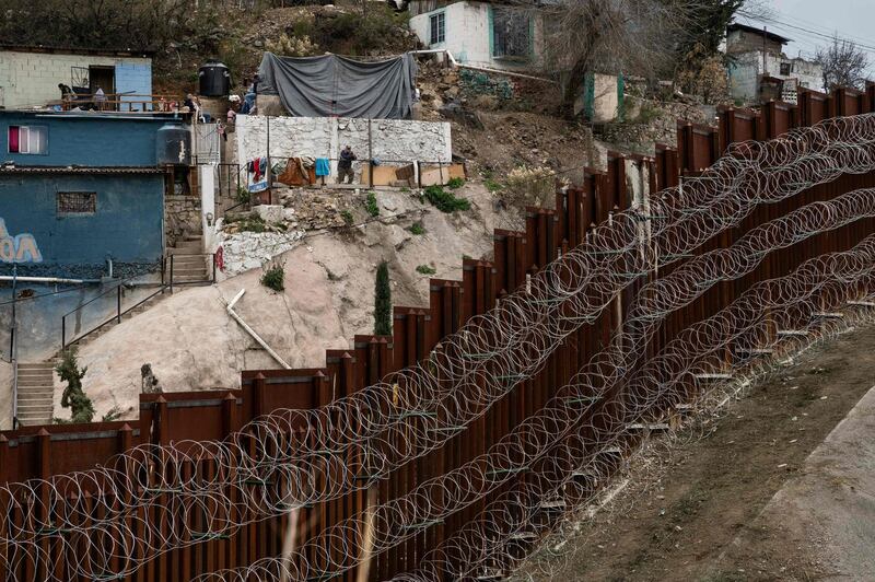 A man looks at the US/Mexico border fence covered in barbed wire from a house on the Mexican side, as seen from Nogales, Arizona. AFP