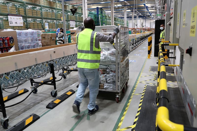 DUBAI, UNITED ARAB EMIRATES , March 18, 2021 –  Staff moving carts at the Amazon DXB3,  Amazon fulfilment centre  in Dubai Logistics City in Dubai. (Pawan Singh / The National) For Lifestyle/Online/Instagram. Story by Farah