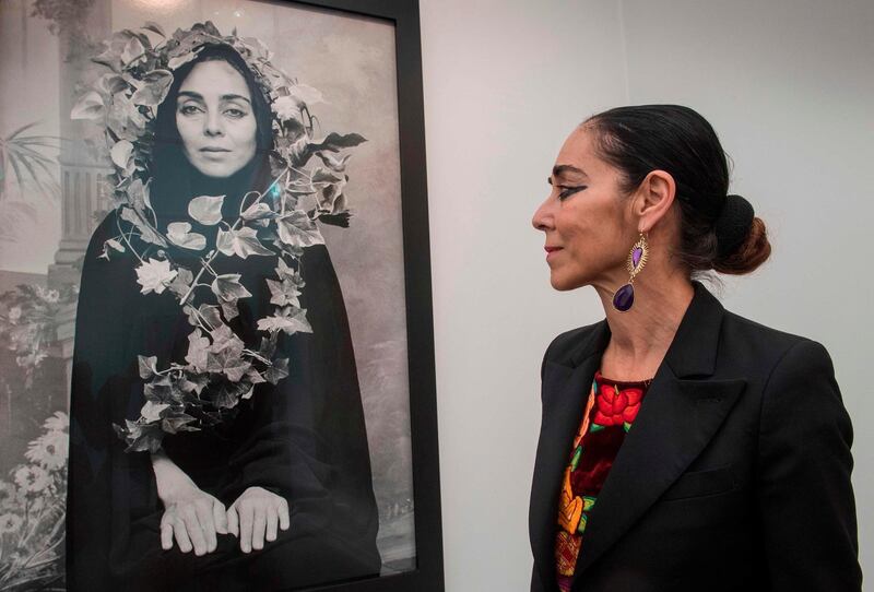 Iranian visual artist Shirin Neshat stands next to an untitled work from her "Women of Allah" series, during the Frieze Los Angeles 2020 art fair in Los Angeles, California, on February 14, 2020.  An anti-white supremacist silent disco broke out on Hollywood's oldest major studio lot on February 14 as Frieze Los Angeles, a major art fair, opened its doors to A-listers and collectors. - RESTRICTED TO EDITORIAL USE - MANDATORY MENTION OF THE ARTIST UPON PUBLICATION - TO ILLUSTRATE THE EVENT AS SPECIFIED IN THE CAPTION
 / AFP / Mark RALSTON / RESTRICTED TO EDITORIAL USE - MANDATORY MENTION OF THE ARTIST UPON PUBLICATION - TO ILLUSTRATE THE EVENT AS SPECIFIED IN THE CAPTION
