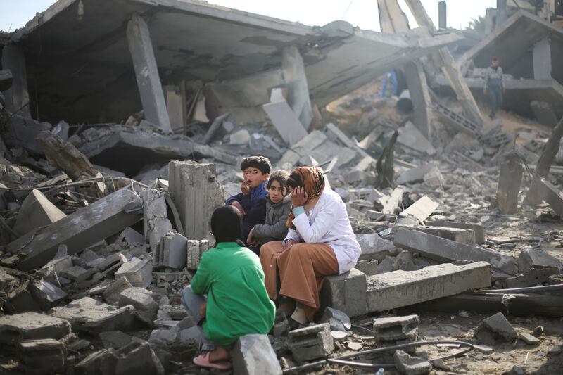 Palestinians sit in the ruins of their home in Rafah after Israeli bombardment of the city. AP