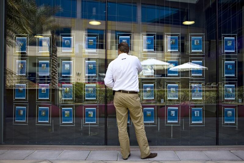 A customer browses the selection of property adverts posted at the Better Homes office in the Gold and Diamonds Souk in Dubai. Lauren Lancaster /The National

