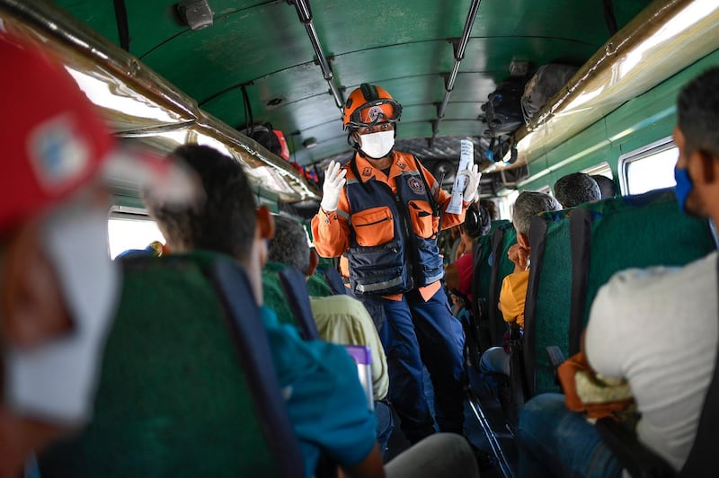 A member of the Venezuelan civil protection agency explains to commuters symptoms and preventive measures for the new coronavirus in Caracas, Venezuela. AP Photo