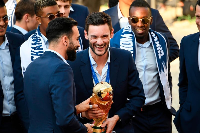 France's goalkeeper Hugo Lloris (C) smiles and holds the trophy as he arrives with teammates for a reception at the Elysee Presidential Palace on July 16, 2018 in Paris after French players won the Russia 2018 World Cup final football match. France celebrated their second World Cup win 20 years after their maiden triumph on July 15, 2018, overcoming a passionate Croatia side 4-2 in one of the most gripping finals in recent history. / AFP / Lionel BONAVENTURE
