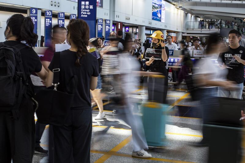 Travellers walk past demonstrators at Hong Kong International Airport. Bloomberg