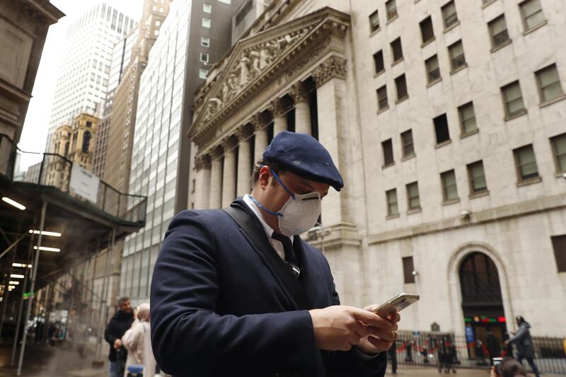 FILE PHOTO: A man wears a protective mask as he walks past the New York Stock Exchange on the corner of Wall and Broad streets during the coronavirus outbreak in New York City, New York, U.S., March 13, 2020. REUTERS/Lucas Jackson/File Photo
