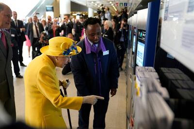 Queen Elizabeth II uses a card machine at Paddington station. AP