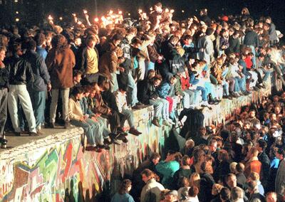 This photo taken on November 11, 1989 in Berlin shows young East Berliners celebrating atop the Berlin Wall. - The fall of the Berlin Wall in 1989, when thousands of Germans joyfully danced atop its graffiti-covered remains, to some heralded the "end of history" in a globalised world. Thirty years later, the return of hard frontiers made of bricks, concrete and razor wire symbolises stark new political realities that are a far cry from the West's heady optimism in the era when the Soviet bloc imploded. (Photo by STR / dpa / AFP) / Germany OUT