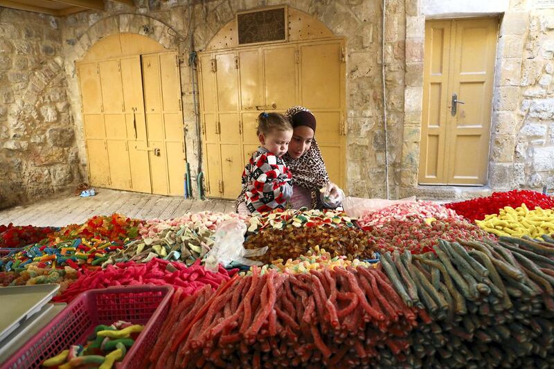 A Palestinian girl and her sibling shop for candy in the old city of the West Bank city of Hebron on April 28, 2020, during Muslim holy month of Ramadan. (Photo by HAZEM BADER / AFP)