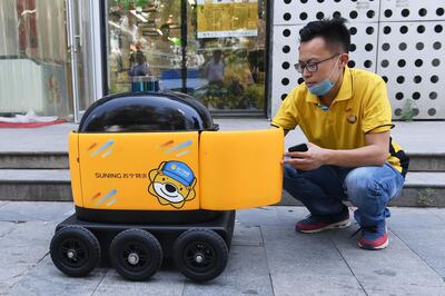 In this photo taken on June 28, 2018, a Suning worker loads a delivery robot with groceries outside a Suning supermarket during a demonstration of the robot in Beijing. Along a quiet residential street on the outer edges of Beijing, a yellow and black cube about the size of a small washing machine trundles leisurely to its destination. This "little yellow horse" is an autonomous delivery robot, ferrying daily essentials like drinks, fruit and snacks from the local store to the residents of the "Kafka" compound in the Chinese capital.
 - TO GO WITH AFP STORY CHINA-TECHNOLOGY-ROBOTS-CONSUMER-SCIENCE,FEATURE BY LUDOVIC EHRET
 / AFP / GREG BAKER / TO GO WITH AFP STORY CHINA-TECHNOLOGY-ROBOTS-CONSUMER-SCIENCE,FEATURE BY LUDOVIC EHRET
