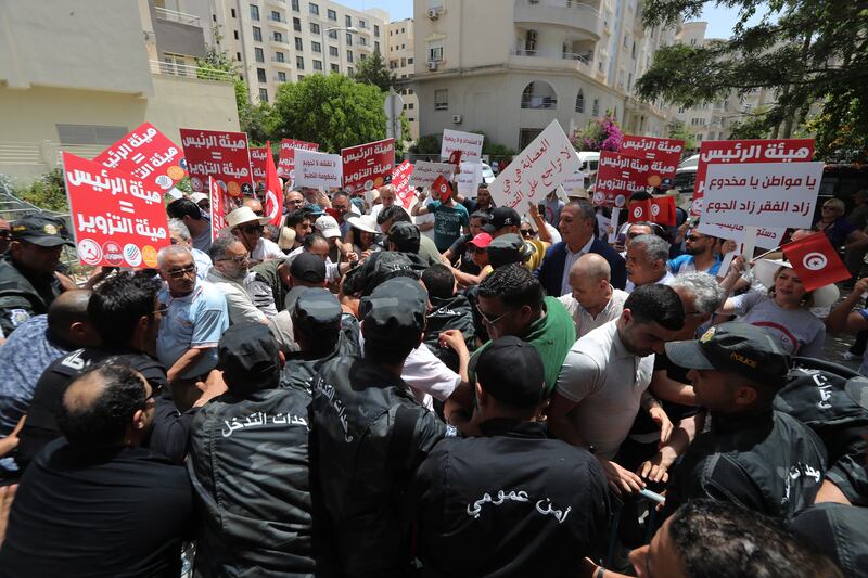 Protesters try to break through security barriers to reach the entrance to the headquarters of the Independent High Authority for Elections in Tunis. EPA