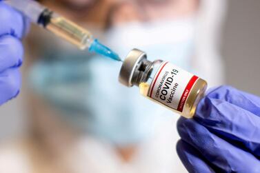 A woman holds a small bottle labelled with a "Coronavirus Covid-19 Vaccine" sticker and a medical syringe, October 30, 2020. REUTERS