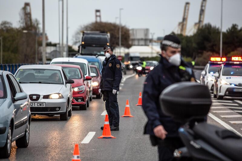 Police officers wear protective face masks as they direct traffic through a checkpoint in Barcelona, Spain. Bloomberg